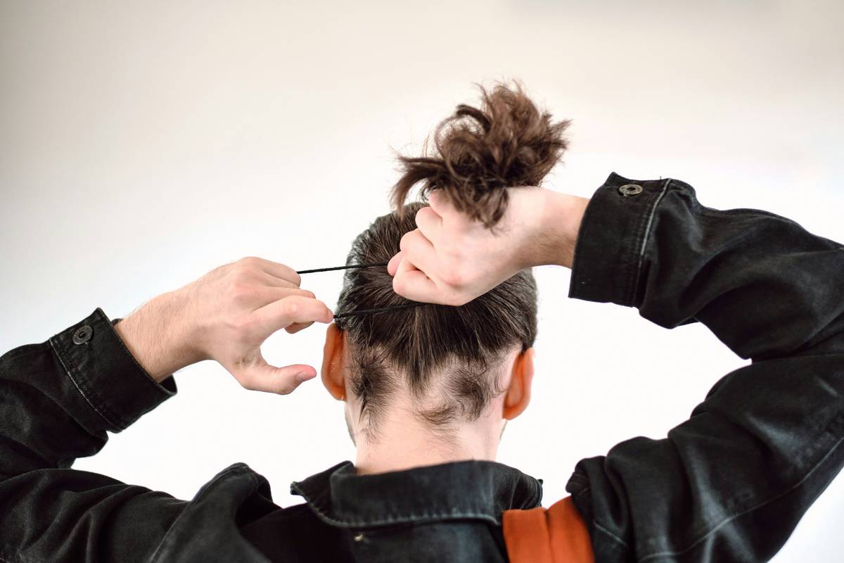 Woman using a gold hair barrette for quick hair fixes while running out the door